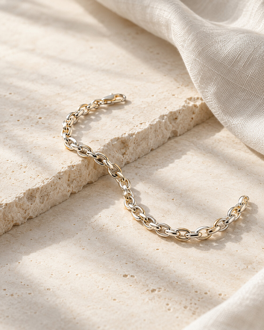 Silver bracelet-inspired editorial still life on warm limestone