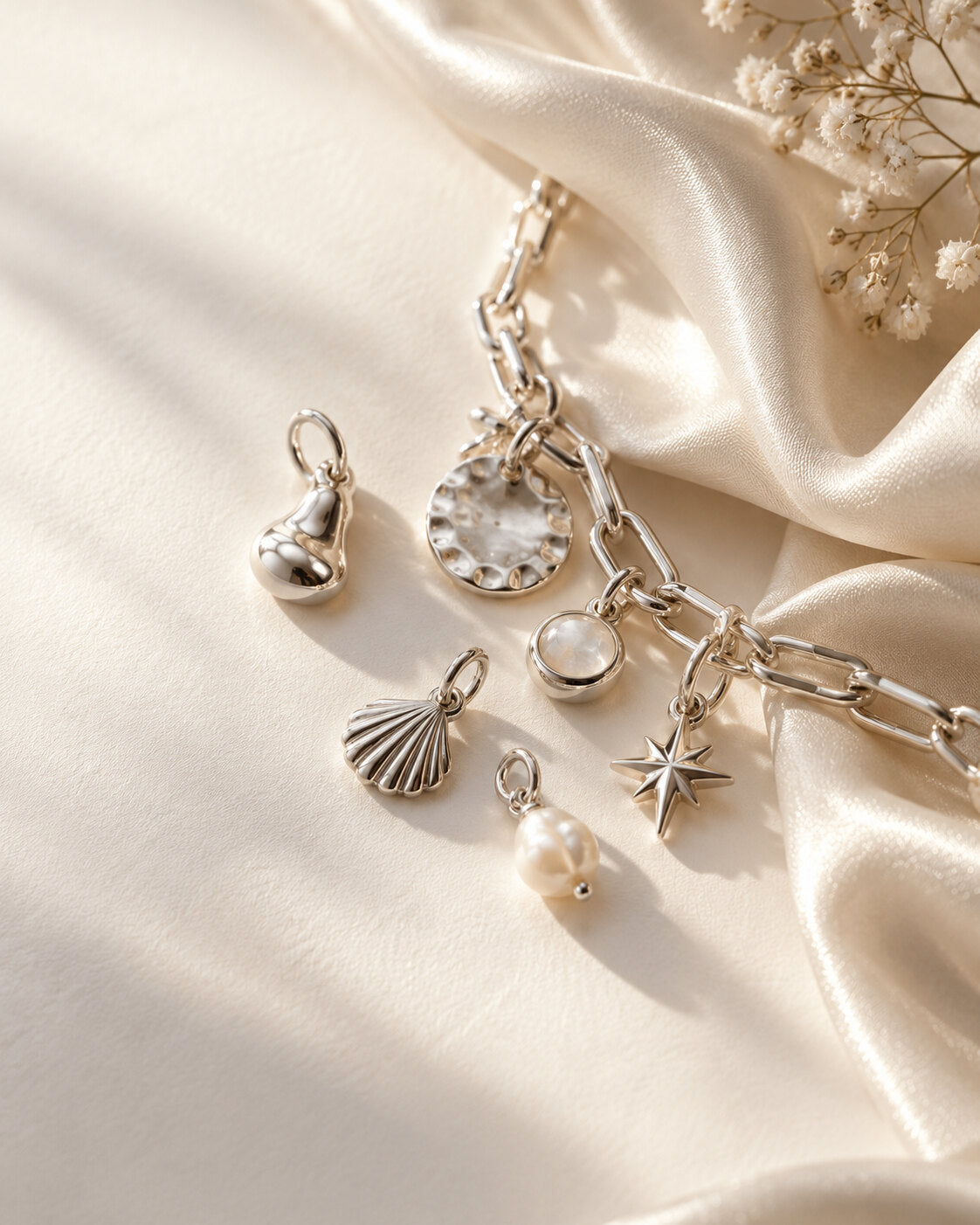 Silver charm-inspired editorial still life on champagne ivory silk